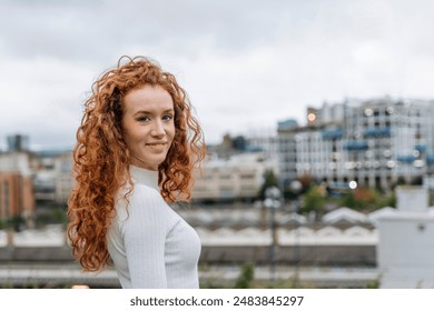 Young Woman With Red Curly Hair Smiles in Urban Setting on Cloudy Day - Powered by Shutterstock