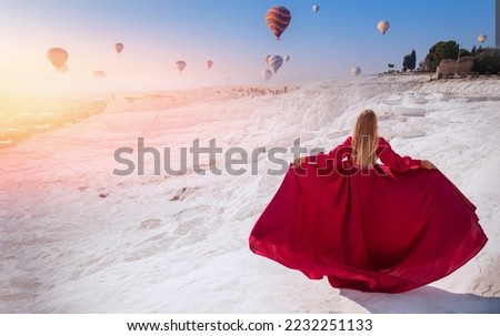 Young Woman in red dress background Pamukkale Hot air balloon flying Travertine pool and terraces sunset. Concept Travel Turkey.