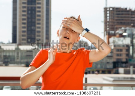 Young woman in a red dress holding on to the head on the background of the city, concept, problems, troubles