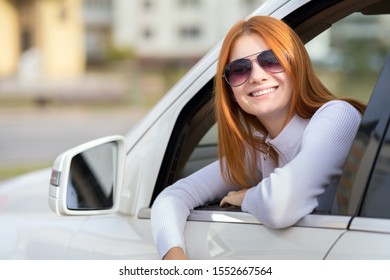 Young woman with red hair driving a car.