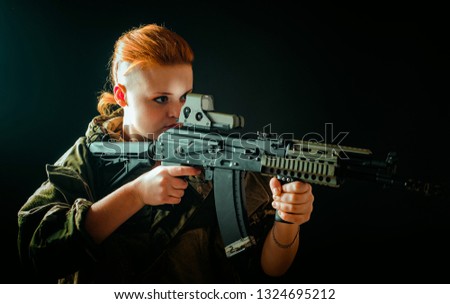 Young woman with red hair, young girl takes aim at the sight in military uniform