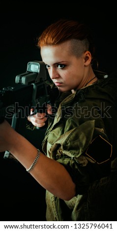 Young woman with red hair, young girl takes aim at the sight in military uniform. Vertical photo