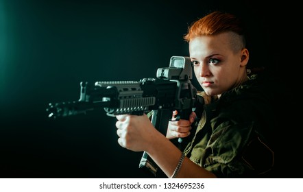 Young woman with red hair, hold machinegun in hands in military uniform