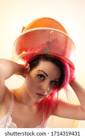 Young Woman With Red Hair Sitting Under A Hood Hair Dryer