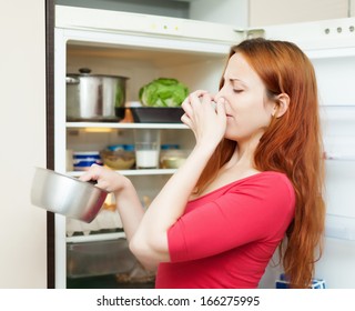  Young Woman In Red  Holding Her Nose Because Of Bad Smell From Food Near Refrigerator  At Home