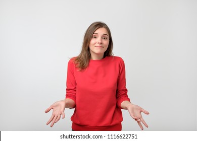 Young woman in red sweater standing disorientated bewildered isolated on gray wall background. Decision making concept. Human facial expression emotions - Shutterstock ID 1116622751