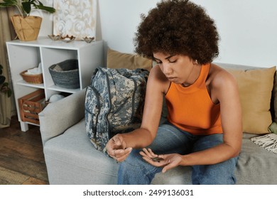 A young woman reflects quietly in her living room as she prepares for her military journey. - Powered by Shutterstock