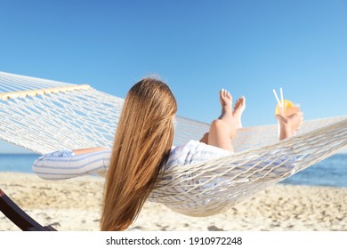 Young woman with refreshing cocktail relaxing in hammock on beach - Powered by Shutterstock