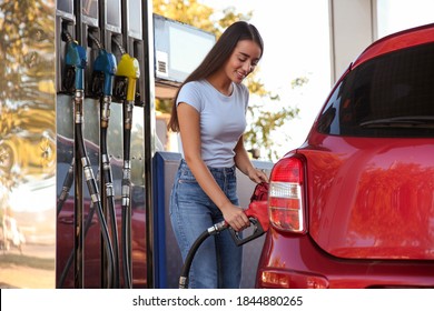 Young woman refueling car at self service gas station