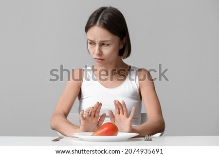 Young woman refusing from food on grey background. Anorexia concept Imagine de stoc © 