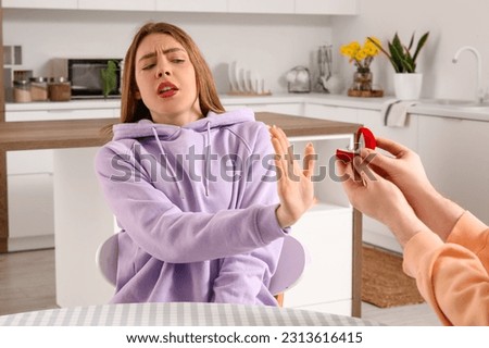 Young woman rejecting marriage proposal in kitchen