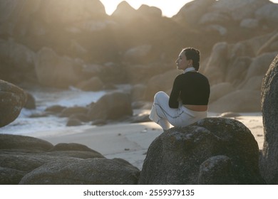 Young woman relaxes on a rocky shore at sunset, taking in the tranquil beach and reflecting on life in the serene coastal scenery - Powered by Shutterstock