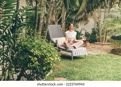 Young woman relaxes on a sun lounger in the garden. Meditation in the garden.