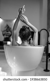 Young Woman Relaxing In The Beautiful Vintage Bath Full Of Foam In The Retro Bathroom Decorated With Candles