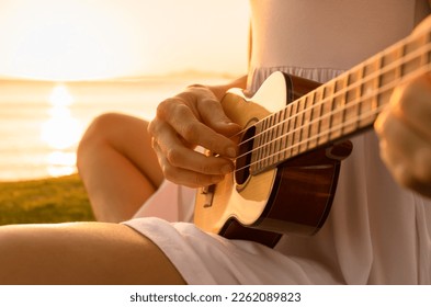 Young woman relaxing by the sea playing guitar on the beach  - Powered by Shutterstock