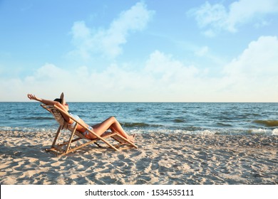 Young woman relaxing in deck chair on beach - Powered by Shutterstock