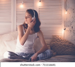 Young  Woman Relaxing In Her Bed, She Is Listening To Music 