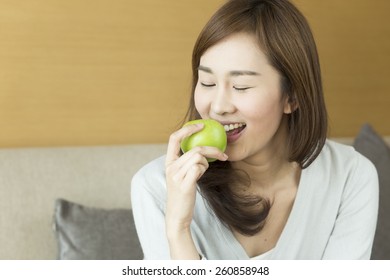 Young woman relaxing at home eating apple