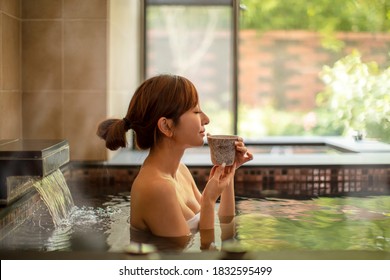 Young woman relaxing in hot spring and drinking tea