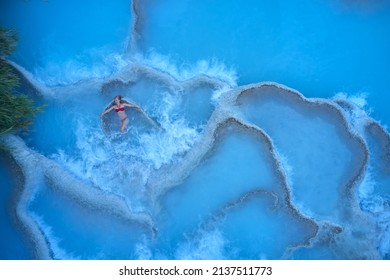 young woman relaxing at natural spa with waterfalls and hot springs at Saturnia thermal baths, Grosseto, Tuscany, Italy - aerial view - Powered by Shutterstock