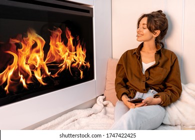 Young woman relaxing near the fireplace at the modern living room at home
