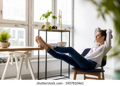 Young woman relaxing in office with her bare feet on desk 
