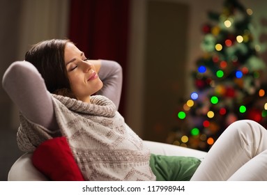 Young woman relaxing on chair in front of Christmas tree