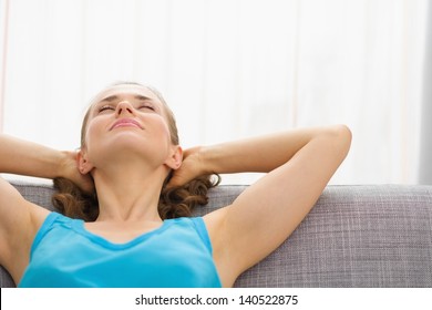 Young Woman Relaxing On Couch In Living Room