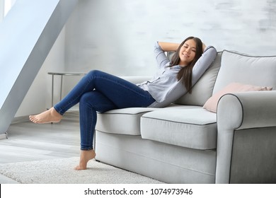 Young woman relaxing on cozy sofa in light room