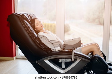 Young woman relaxing on the massaging chair at home