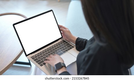 Young Woman Relaxing On Sofa And Surfing Internet With Laptop Computer. Over Shoulder Closeup View.