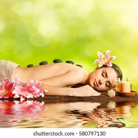 Young woman relaxing in spa salon and reflection on water surface