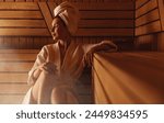 Young woman relaxing and sweating in hot sauna wrapped in towel. Girl In Sauna. Interior of Finnish sauna, classic wooden steam room with hot steam. Russian bathroom. Relax in hot Bathhouse with steam