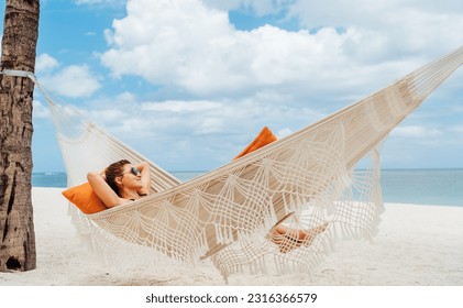 Young woman relaxing in wicker hammock on the sandy beach on Mauritius coast and enjoying wide ocean view waves. Exotic countries vacation and mental health concept image. - Shutterstock ID 2316366579