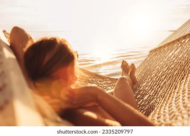 Young woman relaxing in wicker hammock on the sandy beach on Mauritius coast and enjoying sunset light over Indian ocean waves. Exotic countries vacation and mental health concept image.  - Powered by Shutterstock