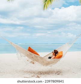 Young woman relaxing in wicker hammock on the sandy white beach on Mauritius coast and enjoying wide ocean view waves. Exotic countries vacation and mental health concept image. - Powered by Shutterstock
