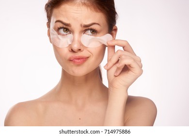 young woman removes patches under the eyes on a light background portrait                               