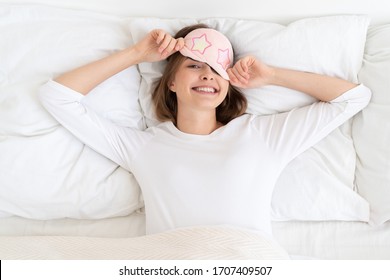 Young Woman Removing Sleeping Mask From Eyes After Night Sleep, Lying In Bed In Morning, Looking At Camera With Happy Face, Aspiring For Great Positive Day