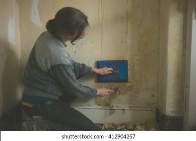 A Young Woman Is Removing Wallpaper With A Steamer