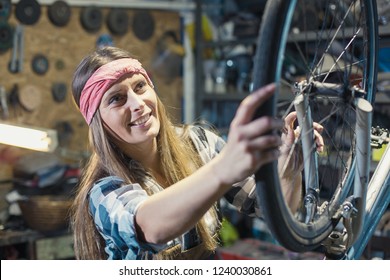 young woman repairing bicycle wheel - Powered by Shutterstock