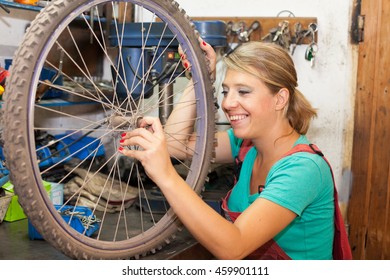 young woman repairing bicycle wheel - Powered by Shutterstock