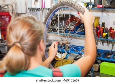 young woman repairing bicycle wheel - Powered by Shutterstock