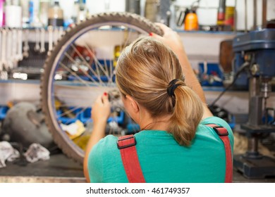 young woman repairing bicycle wheel - Powered by Shutterstock