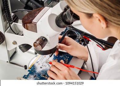 Young woman repairing computer components in service center. Repairing and fixing service in lab. Electronics repair service concept. - Powered by Shutterstock