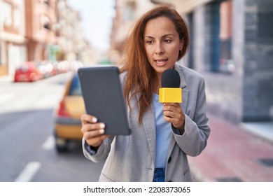 Young Woman Reporter Working Using Microphone And Touchpad At Street