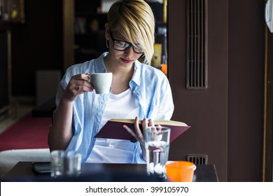 Young woman in a restaurant reading a book  - Powered by Shutterstock
