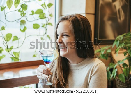 Young Woman In A Restaurant Smiling And Drinking A Cocktail