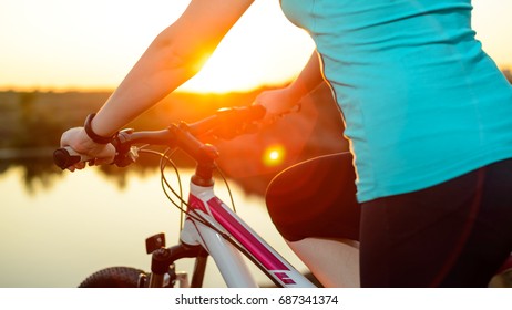 Young Woman Resting with Mountain Bike on the Summer Rocky Trail at Sunset. Closeup of Hands with Smart Watch on the Handlebar. Training and Sports Concept. - Shutterstock ID 687341374