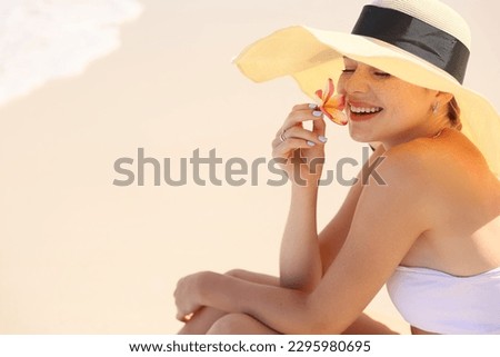 Young woman is resting on the beach. Happy island lifestyle. girl sitting on the shore wearing a hat and holding a flower