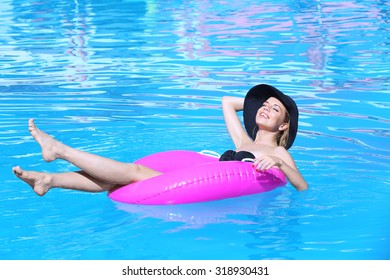 Young Woman Resting On Pink Rubber Ring In Swimming Pool